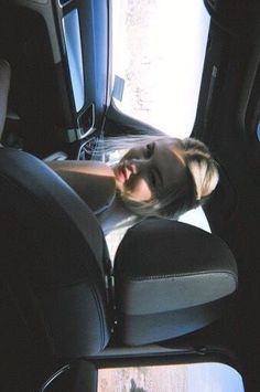 a woman is sitting in the back seat of a car with her eyes closed and mouth open