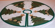 a quilted christmas tree skirt on top of a white table cloth with green trim