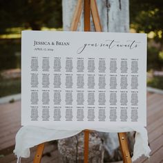 a wooden easer with a seating chart on it sitting in front of a tree