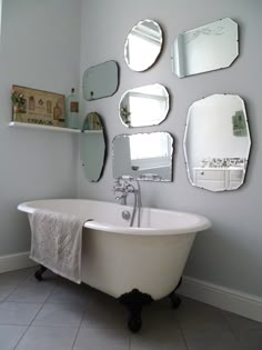 a white bath tub sitting next to a wall with mirrors on it