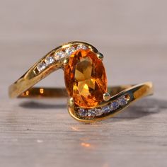 an orange and white diamond ring sitting on top of a wooden table