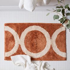 a bathroom rug with circles on it next to a towel rack and toilet paper roll