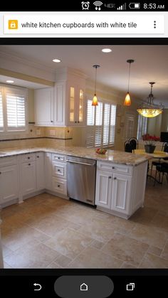 a large kitchen with white cabinets and marble counter tops, along with an island in the middle