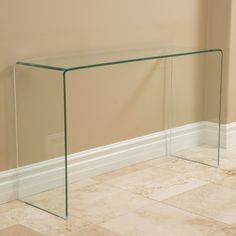 a glass console table sitting on top of a tiled floor next to a beige wall