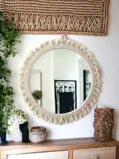 a mirror on the wall next to a dresser and potted plant in front of it