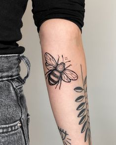 a woman's arm with a bee tattoo on it