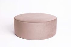 a round pink ottoman sitting on top of a white floor