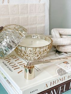 a stack of books with a candle on top of it next to a glass bowl