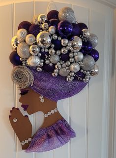 a woman's head is adorned with purple and silver ornaments, as she stands in front of a white door