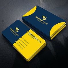 two blue and yellow business cards sitting on top of a black table next to each other