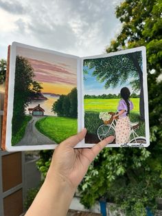 a person holding up an open book with pictures on the pages and a painting of a woman riding a bike