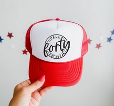 a person holding up a red and white trucker hat