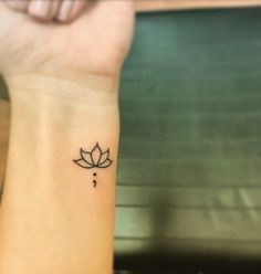 a woman's wrist with a small lotus tattoo on the left side of her arm