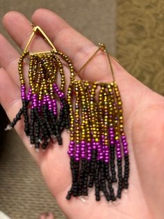 Dangling earring.  Purple, gold, and black beaded.  Hand made. Gold Beaded Dangling Earrings For Festival, Gold Beaded Festival Earrings, Handmade Black Dangle Hoop Earrings, Metal Beaded Earrings For Party, Black Dangle Hoop Earrings For Party, Black Dangle Jewelry For Festivals, Black Dangle Jewelry For Festival, Purple Jewelry With Black Beads For Festival, Purple Festival Jewelry With Black Beads