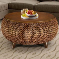 a wicker coffee table with fruit on top in a living room setting by a couch