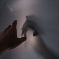 a hand reaching for something in the air with it's shadow on the wall