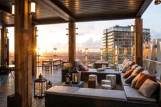 an outdoor seating area with couches, tables and chairs on top of a building