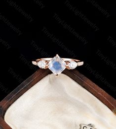 an engagement ring with two pear shaped diamonds in it on top of a wooden box