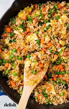 a skillet filled with rice, peas and carrots