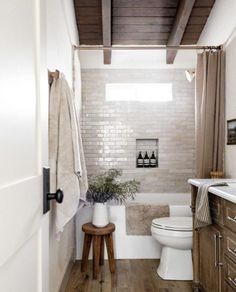 a white toilet sitting next to a bath tub in a bathroom under a wooden ceiling