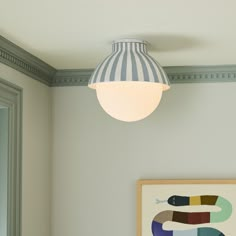 a light fixture hanging from the ceiling in a room with a painting on the wall