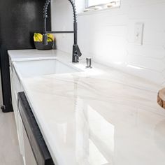 a white kitchen counter top with a black faucet