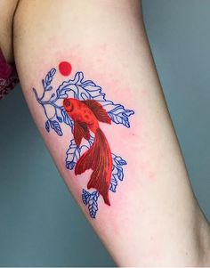 a woman's arm with a red fish tattoo on it