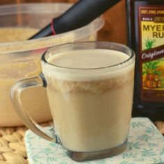 a cup of coffee sitting on top of a table next to a bottle of syrup