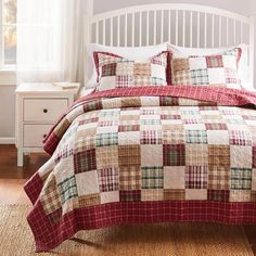 a bed with a red and green plaid quilt on it's coverlet next to a window