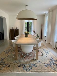 a dining room table with white chairs and an area rug