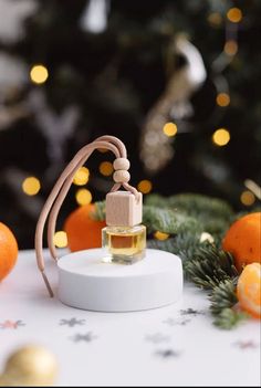 a bottle of perfume sitting on top of a table next to an orange and christmas tree