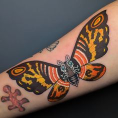 a colorful butterfly tattoo on the arm with an orange and black stripe around it's wings