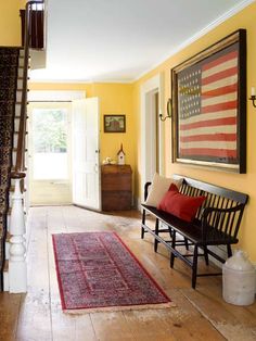 a hallway with yellow walls and red rugs on the floor, along with an american flag painting