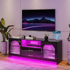 a living room with a large television and purple lighting on the sideboard in front of it