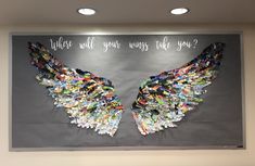 an art piece is displayed on the wall in front of a sign that says, what will your wings take you?