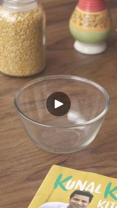 a book is sitting on a table next to a glass bowl with cereal in it