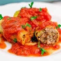 stuffed cabbage rolls with tomato sauce and parsley on a white plate, ready to be eaten