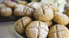 a plate full of powdered sugar cookies on top of a table with other pastries in the background