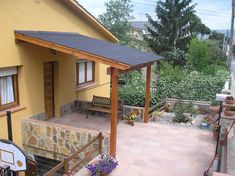 a yellow house with a wooden porch and covered patio