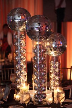 disco ball centerpieces with candles and place settings on a table at a party