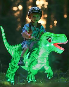 a young boy riding on the back of a green dinosaur toy in the dark forest