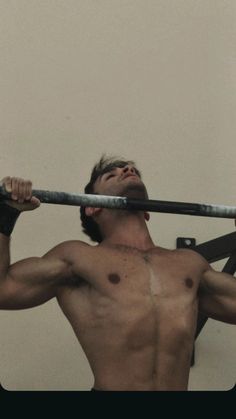 a shirtless man holding onto a metal bar