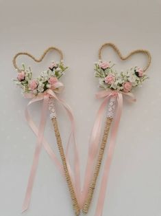 two heart shaped hair pins with flowers and ribbons on them, tied in twine