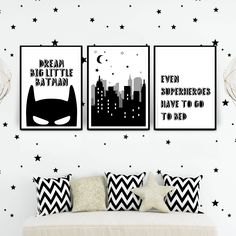 two batman posters are hanging on the wall above a bed in a room with black and white decor