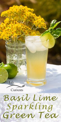 a glass filled with lemonade and lime next to some flowers