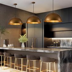 a modern kitchen with marble counter tops and gold pendant lights above the bar stools