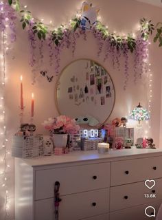 a dresser with flowers and candles on top of it in front of a wall clock