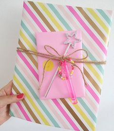 a hand holding a pink gift wrapped in twine and paper with scissors on it