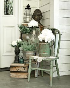 a chair sitting on the front porch with flowers in buckets