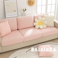 a pink couch with a flower on it in front of a white rug and window